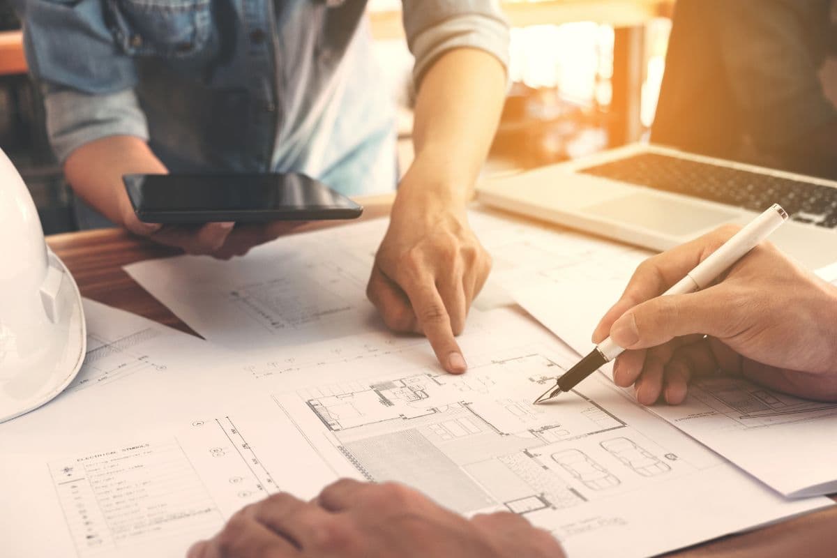 Hands pointing at and annotating architectural floor plans on a desk
